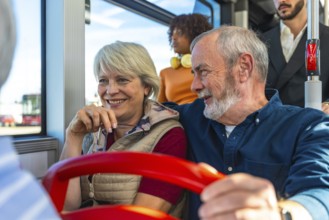 Senior husband and wife smiling and chatting on a daytime city bus, enjoying public transport