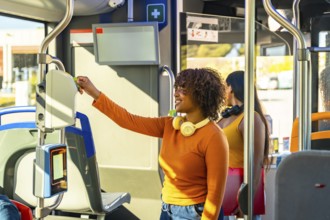 Happy young woman passengers using a smart card on an electronic validator, paying for a journey on
