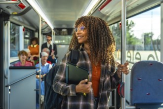 Young black woman with curly hair and glasses smiling, holding a digital tablet and a pole while