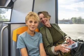 Mother and son sitting inside a bus, sharing a moment while traveling using public transport, the