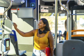Young smiling woman using a payment validator for her ticket or travel card when boarding a city