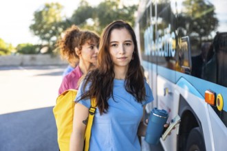 Young female commuters are standing in line, holding a reusable cup and a wallet, waiting to board