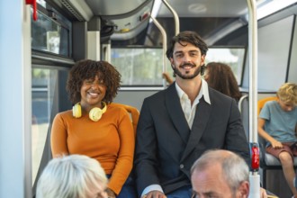 Diverse young couple smiling at camera while seated on a city bus, enjoying their commute and eco