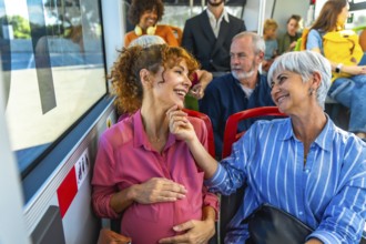 Pregnant woman and senior woman are smiling and talking while traveling on a public bus, sharing a