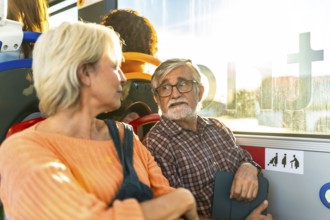 Senior couple sitting on a city bus, chatting and smiling as sunlight streams through the window