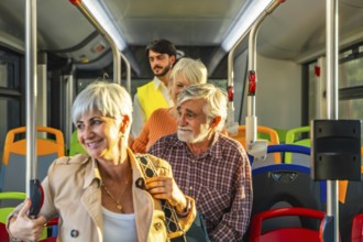 Seniors with gray hair and a younger man riding a modern public bus, holding onto vertical poles