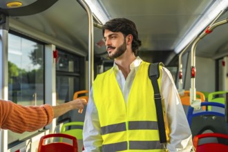 Young man standing inside a public bus. Wearing a yellow high visibility safety vest and carrying a
