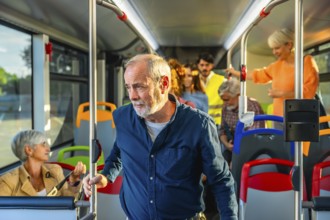 Senior man standing inside a public transport bus, holding a pole and looking contemplative while