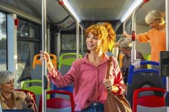 Woman standing on crowded city bus, holding a pole and smiling as she travels through the urban