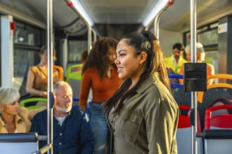 Young woman standing and smiling, riding public transport bus with diverse passengers in