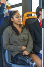 Young woman with a carbon fiber prosthetic leg sitting on public transport, riding a modern bus,