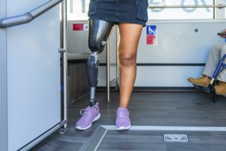 Amputee woman with a prosthetic leg and sneakers standing inside a bus, sharing the accessible