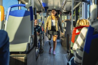 Young woman with a prosthetic leg confidently walking down a bright city bus aisle among seated