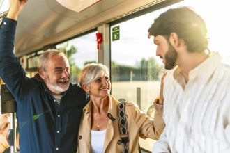Family generations chatting and smiling while standing on a bright city bus, sunlight streaming