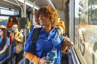 Smiling young black nursing student in blue scrubs with backpack and reusable cup, standing on a