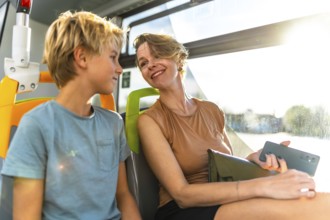 Happy mother and son enjoying a conversation while sharing a seat on a public transport bus, with