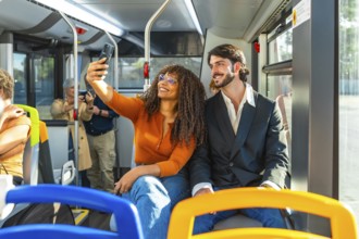 Diverse couple smiling and taking a selfie on a modern city bus during their commute, enjoying