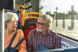 Senior couple chatting and smiling as they travel together on a city bus, enjoying companionship