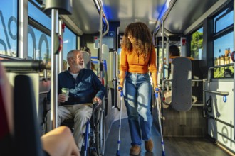 Mature man in wheelchair and young woman using crutches riding inside a modern public