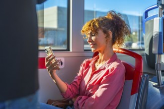 Woman on a city bus smiling while scrolling smartphone, enjoying digital content and staying