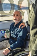 Senior man in a wheelchair receiving assistance from another person, highlighting support and