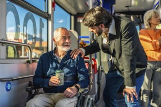 Young man offering assistance and support to a smiling senior man using a wheelchair while