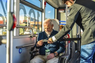 Younger man assisting a senior man in a wheelchair by securing his safety belt, ensuring