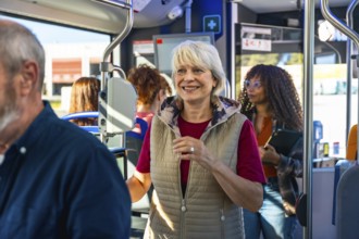 Senior woman smiling confidently, standing on a bustling urban bus alongside other passengers,