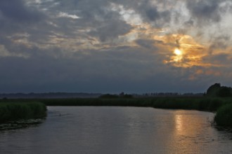 Cloudy sky at sunset over a river with slight reflection, Peenetal nature park Park,