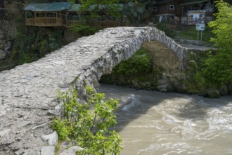 Historic stone bridge crosses bubbling river in forest, Makhuntseti stone arch bridge,