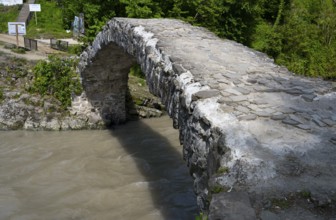 Old stone bridge spanning a river in green surroundings, Makhuntseti stone arch bridge,