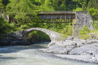 Stone and car bridge crossing a river in a mountainous forest landscape, Purtio stone arch bridge,