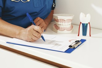 A dentist in a blue uniform studies patient information and prepares for treatment in a modern