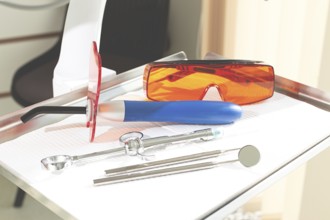 On the tray are various dental instruments, a model dental implant and bright orange safety