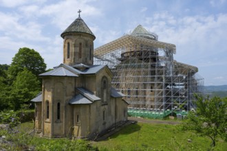 Historic church with scaffolding in green surroundings, presumably a renovation, Gelati monastery
