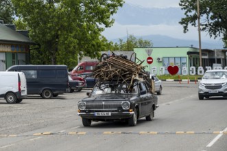 Old car with a load of scrap on the roof is driving on a country road, Imereti region, Imereti,