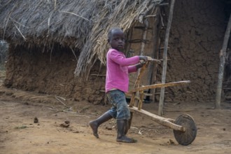 Child playing with a self-made wooden balance bike, in a Sadaani village, Tanga, Tanzania