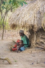 Father and child in front of a simple traditional clay hut in a Sadaani village, Tanga, Tanzania