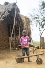 Child playing with a self-made wooden balance bike, in a Sadaani village, Tanga, Tanzania