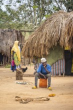 Man sitting on an upturned bucket in a Sadaani village, Tanga, Tanzania