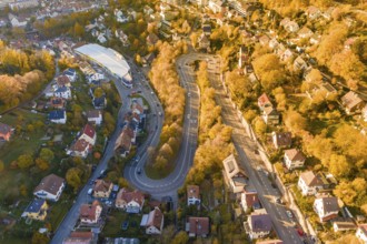 Aerial view of a winding road surrounded by houses and autumn trees in a town, Calw, Black Forest,