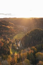 Sunset illuminates a valley with dense forests and a river course in autumn, Calw, Black Forest,