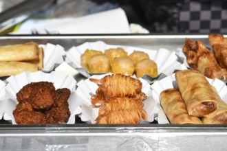 Various small fried Thai street food snacks like springrolls or potato noodle prawns on small trays