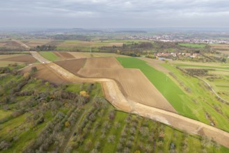 Extensive rural landscape with fields and power lines under a cloudy sky, construction site, the