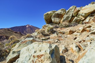 Colorful rock in the foreground against a clear sky and a distant volcano, UNESCO World Heritage