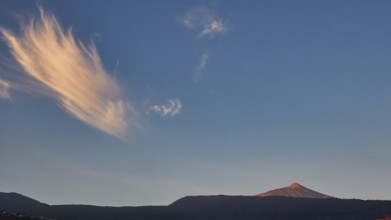 Striped clouds in the evening sky over a distant volcano in soft light, UNESCO World Heritage Site,