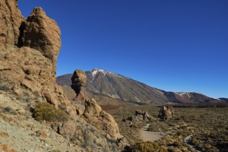 Rocky desert landscape with distinctive rocks and a mountain in the background under clear blue