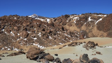 Barren volcanic landscape with rocks and snow trails under clear sky, UNESCO World Heritage Site,