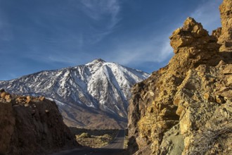 Snow-covered Teide, snowy mountain with road between majestic rocks in clear skies, UNESCO World