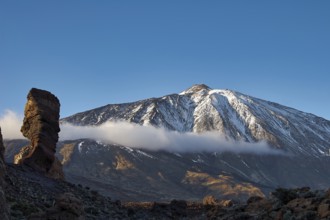 Snow-covered Teide, majestic snowy mountain with rugged rocks in sunlight and clouds above, UNESCO